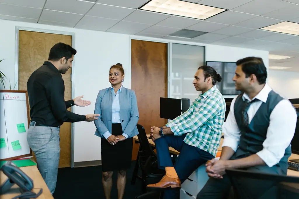 Four colleagues in an office talking through work at a whiteboard